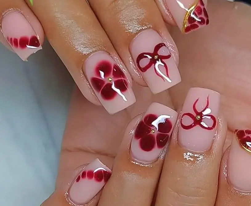 Nude nails with hand-painted red florals and bows